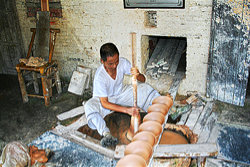 Meister Wang Yansheng beim Drehen an einer in den Boden eingelassenen, von Hand angetriebenen Töpferscheibe im Guyao Museum, Jingdezhen.