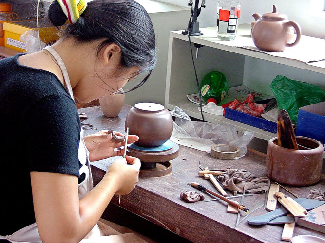 Teekännchenherstellung in Dingshan: Eine junge Frau fertigt Henkel für die gänzlich handgearbeiteten Kännchen.