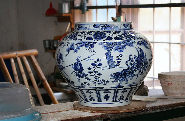 Ein fertig gestelltes Blau–Weiß–Gefäß. Es zeigt Szenen chinesischer Mythen.